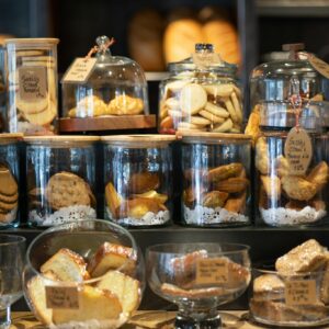 A variety of cookies and pastries artfully displayed in glass jars within a cozy bakery setting.
