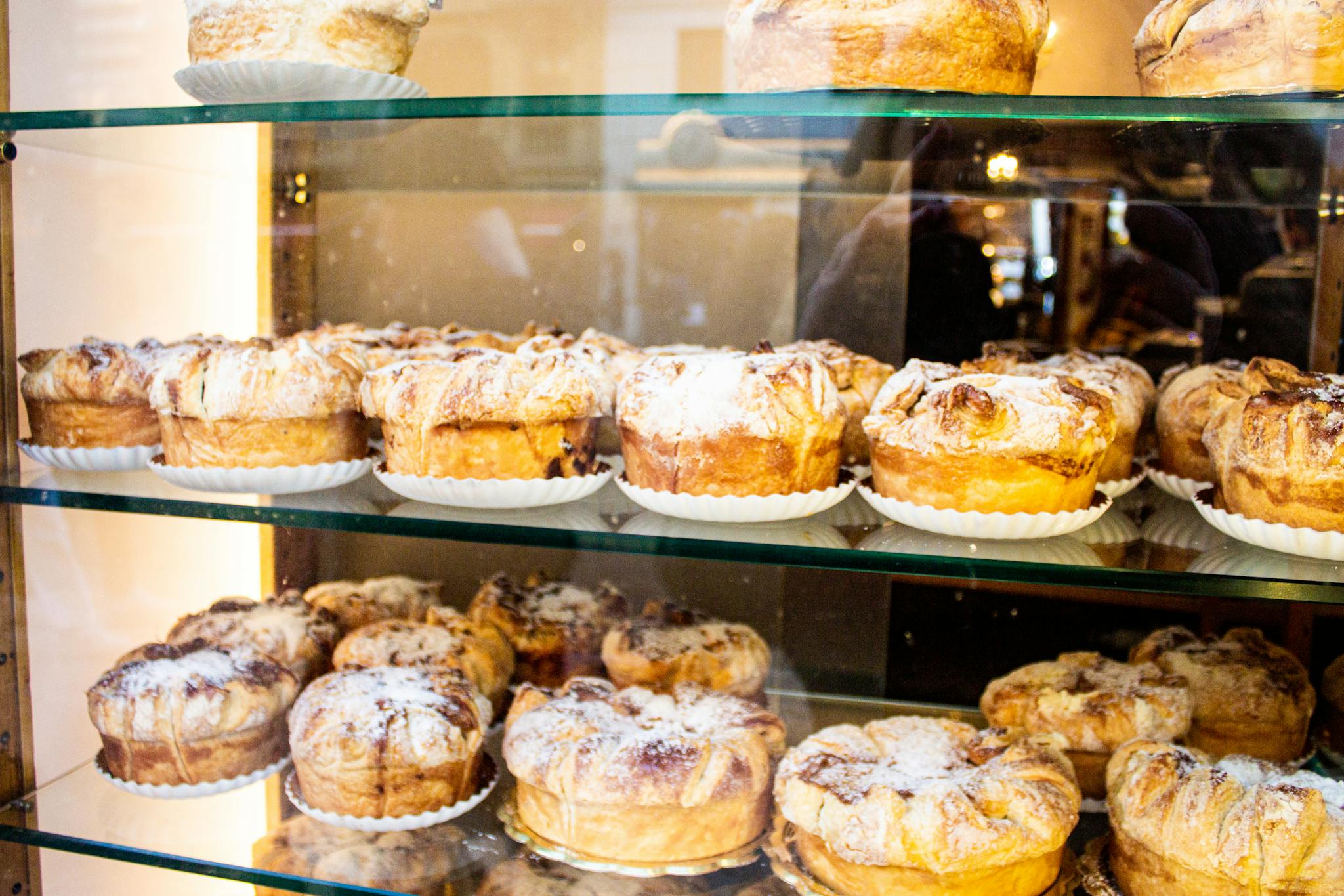 A variety of mouthwatering pastries displayed on glass shelves in a bakery setting.